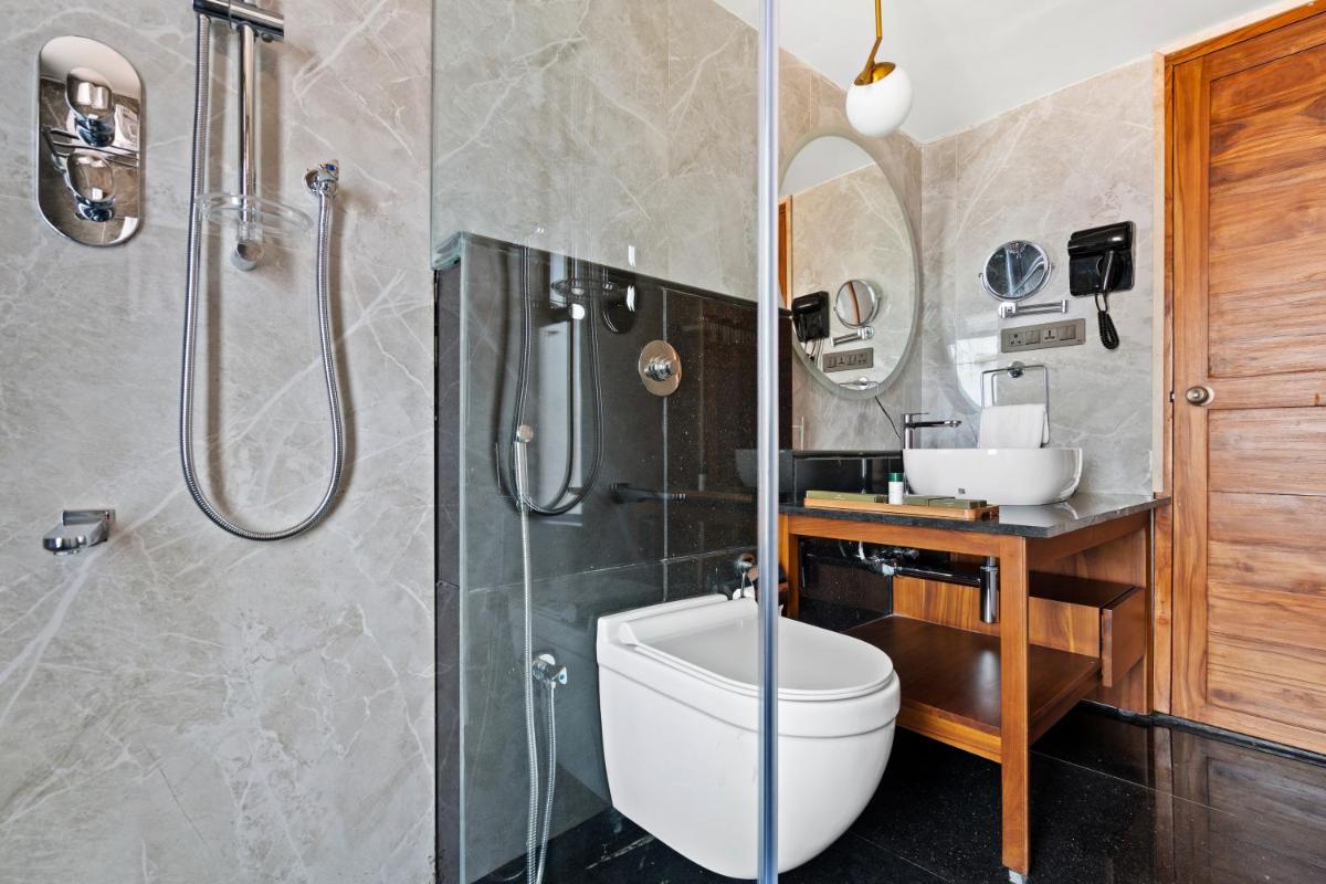 a bathroom with a shower and a toilet and a sink at WelcomHeritage Ayatana Ooty in Ooty