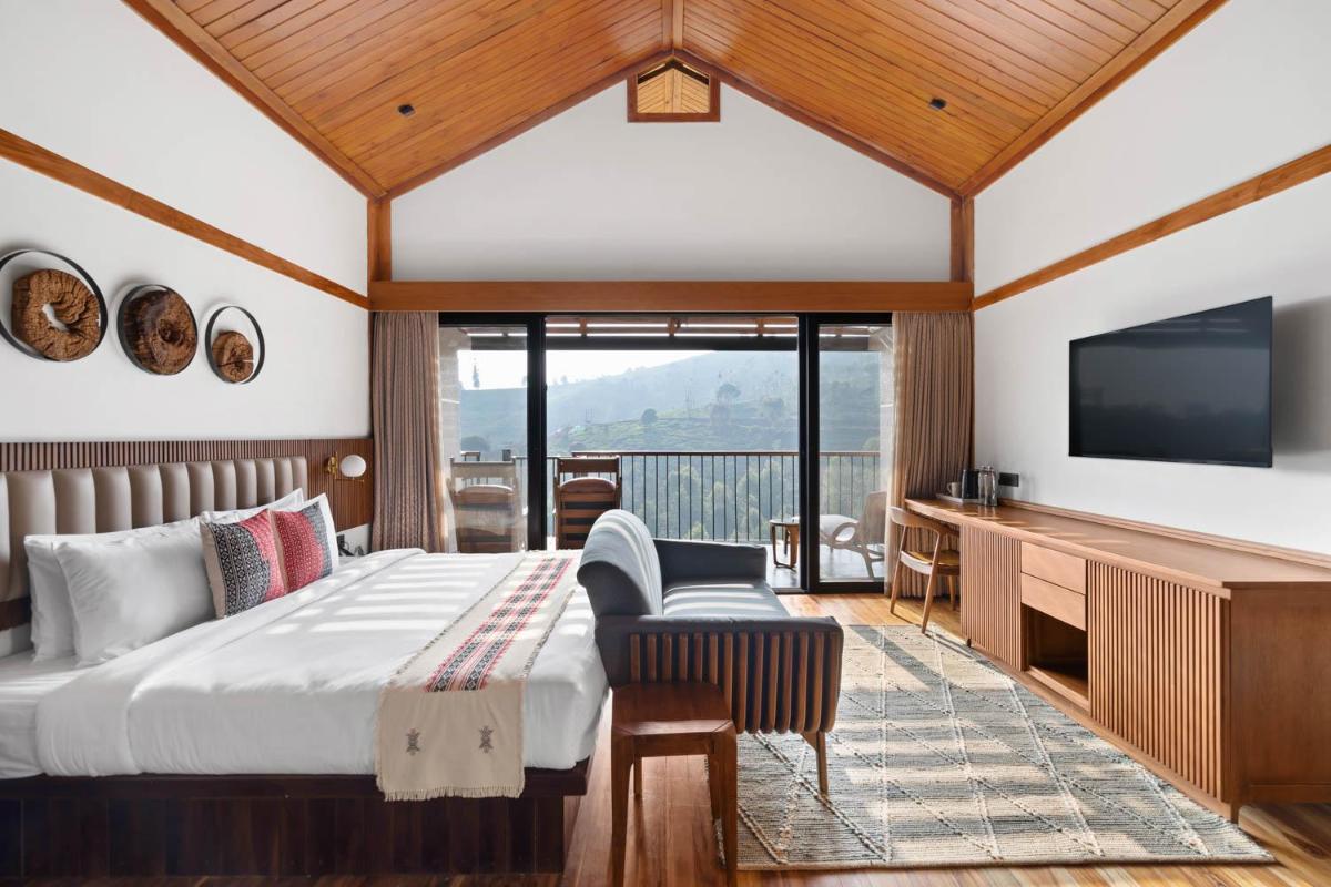 a bedroom with a bed and a flat screen tv at WelcomHeritage Ayatana Ooty in Ooty