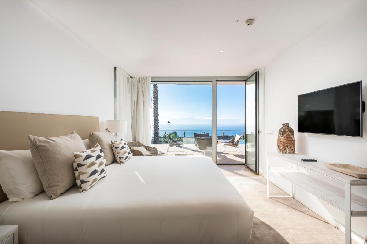 Un dormitorio blanco con una cama grande y un televisor. en Los Jardines de Abama Suites & Villas, en Guía de Isora 37 fotos más