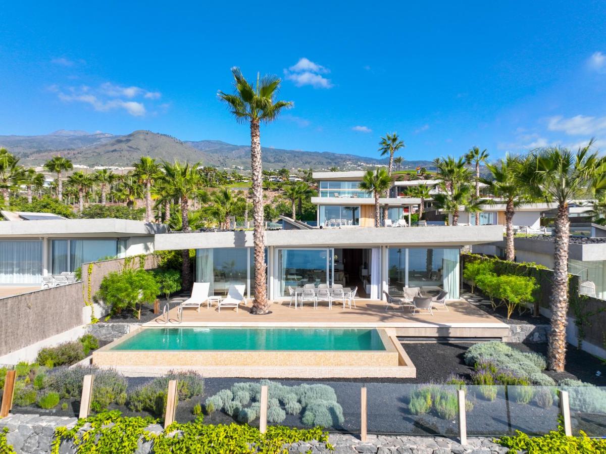 Una vista aérea de una casa con piscina y palmeras. en Los Jardines de Abama Suites & Villas, en Guía de Isora