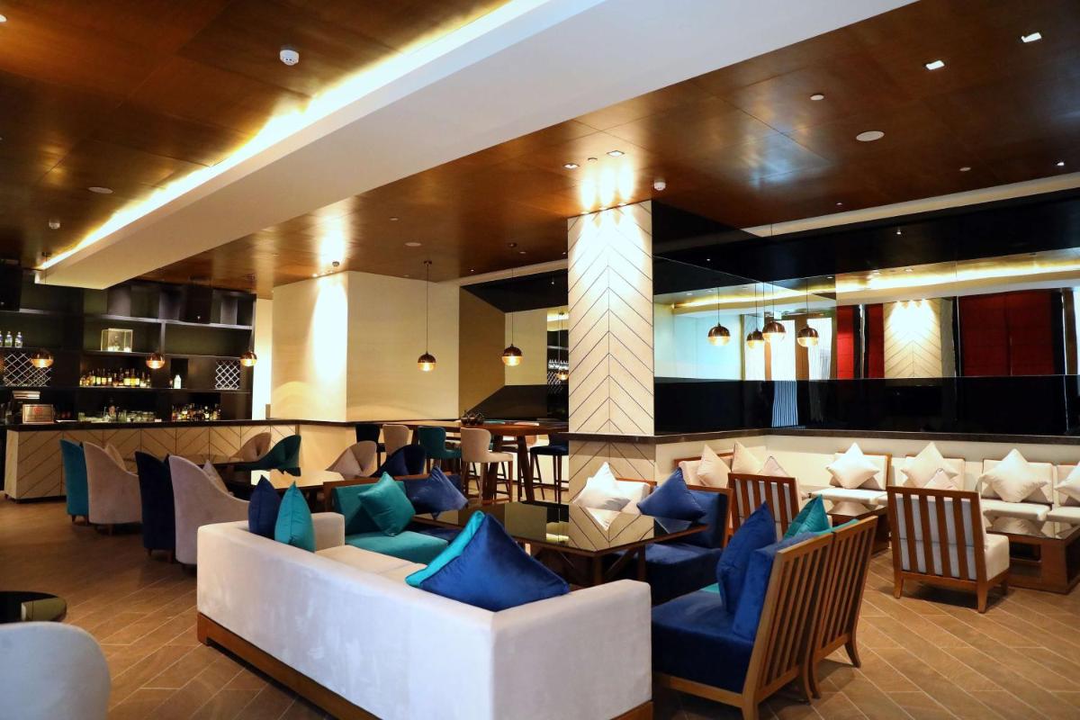 a lobby with couches and chairs and a bar at Hyatt Regency Amritsar Hotel & Spa in Amritsar