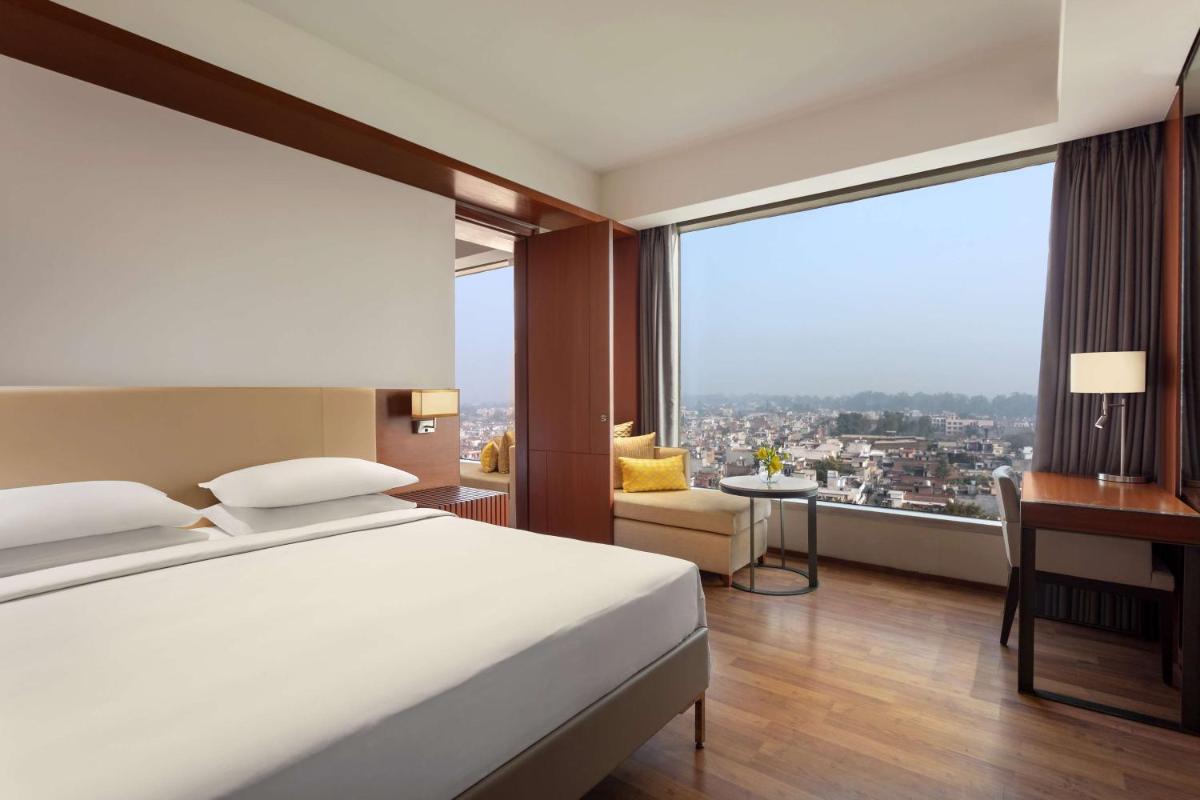 a hotel room with a bed and a large window at Hyatt Regency Amritsar Hotel & Spa in Amritsar