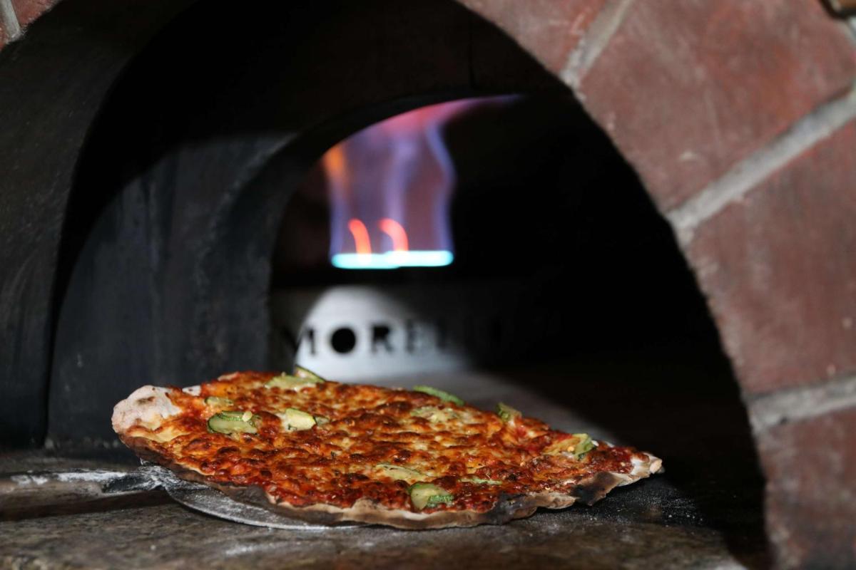 a pizza is coming out of a brick oven at Hyatt Regency Amritsar Hotel & Spa in Amritsar