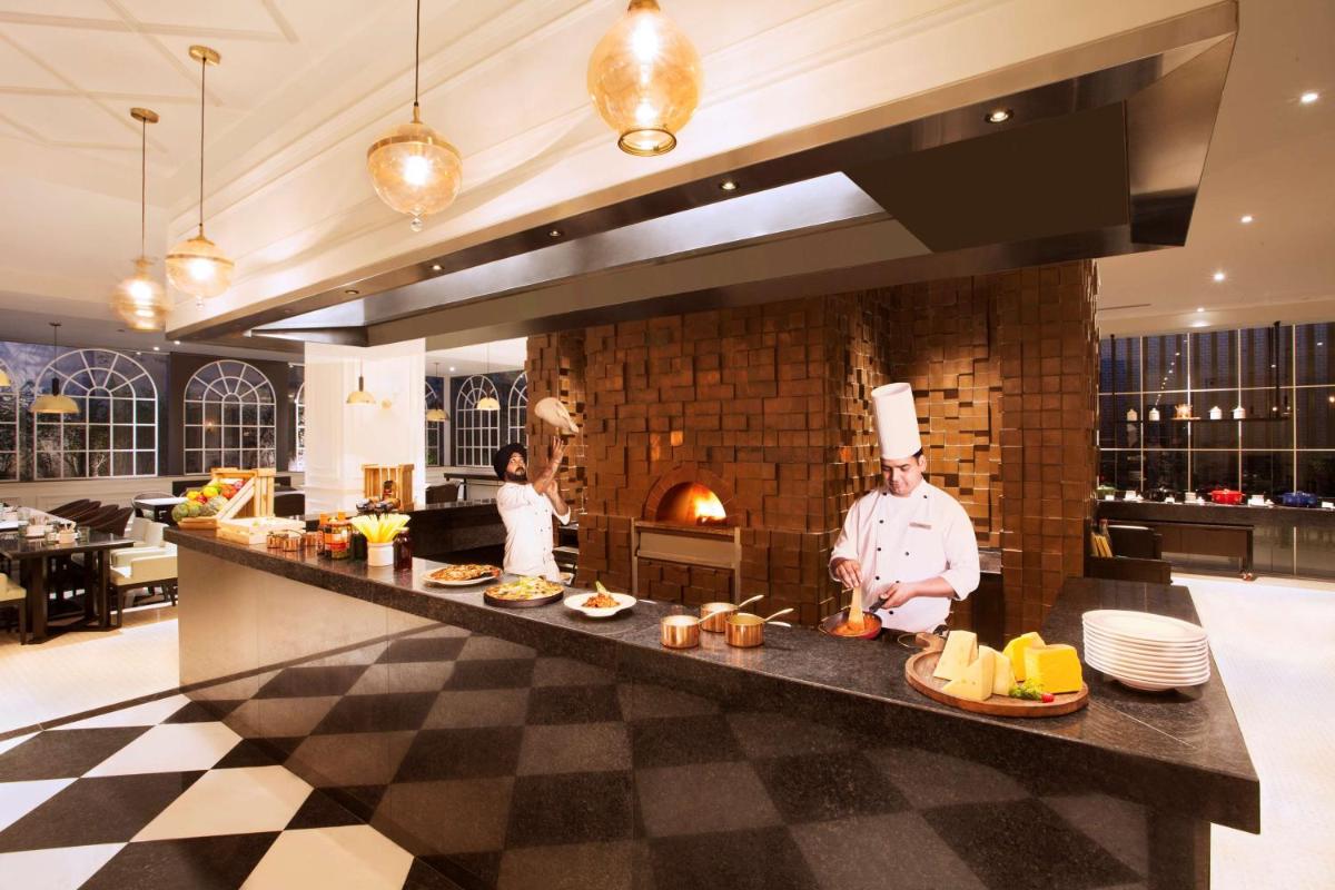 a kitchen with two chefs standing behind a counter at Hyatt Regency Amritsar Hotel & Spa in Amritsar