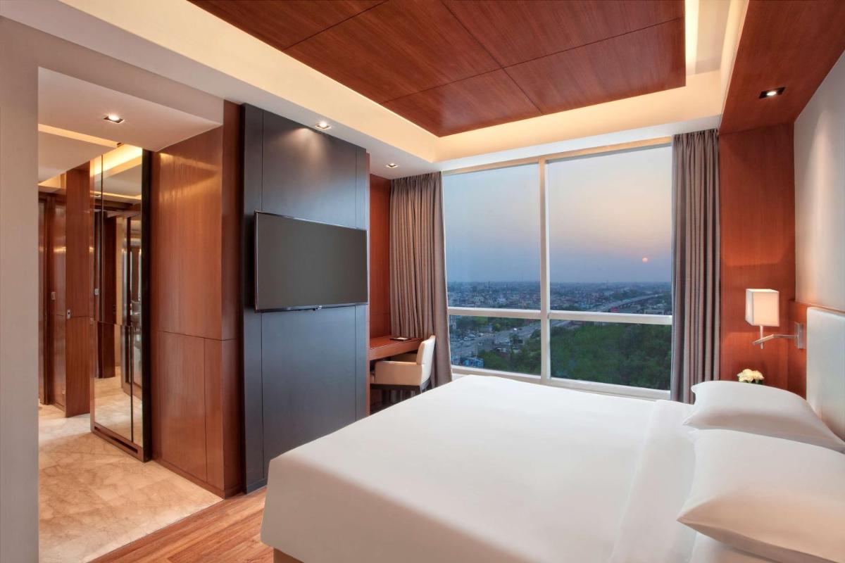 a bedroom with a large white bed and a large window at Hyatt Regency Amritsar Hotel & Spa in Amritsar