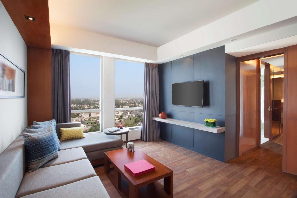 a living room with a couch and a tv at Hyatt Regency Amritsar Hotel & Spa in Amritsar