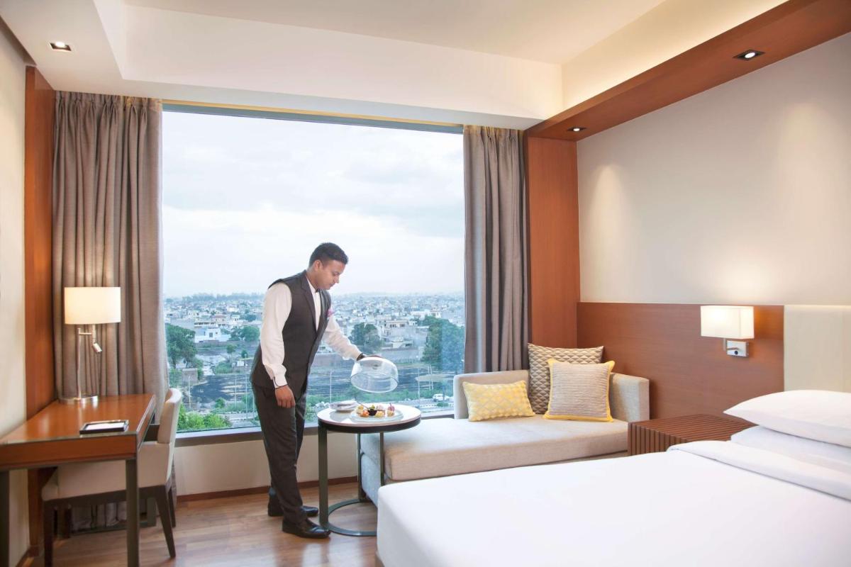 a man standing in a hotel room with a plate of food at Hyatt Regency Amritsar Hotel & Spa in Amritsar