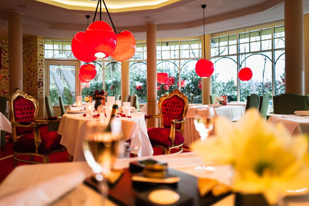 ein Restaurant mit weißen Tischen und roten Stühlen und Fenstern in der Unterkunft Hotel BEI SCHUMANN in Kirschau + 37 Fotos