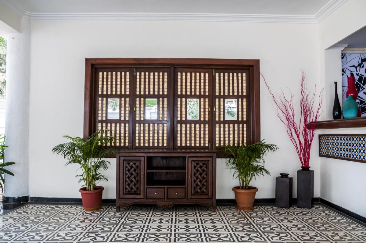 a living room with a wooden cabinet and two plants at Radisson Goa Candolim in Candolim
