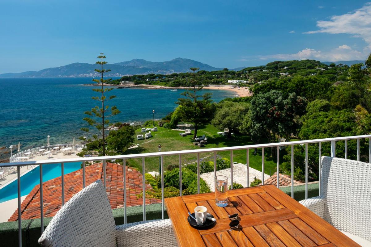- une table sur un balcon avec vue sur l'océan dans l'établissement Hotel Le Maquis, à Porticcio