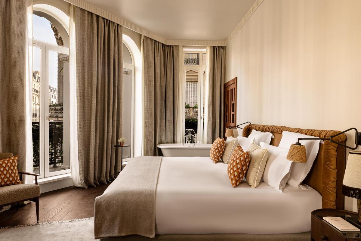 une chambre d'hôtel avec un lit et une baignoire dans l'établissement Château des Fleurs Hôtel & Spa Paris, à Paris une chambre d'hôtel avec un lit et une baignoire dans l'établissement Château des Fleurs Hôtel & Spa Paris, à Paris