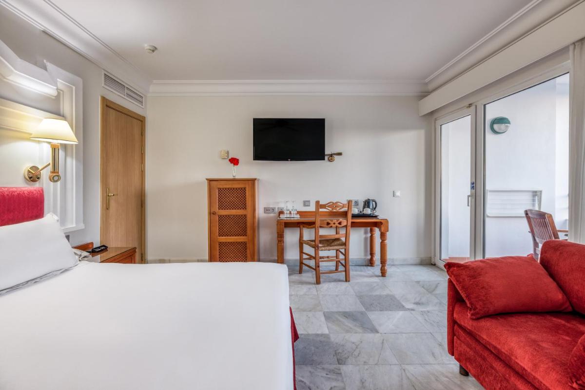 Un dormitorio con una cama y una sala de estar con una mesa. en Playacartaya, en El Portil