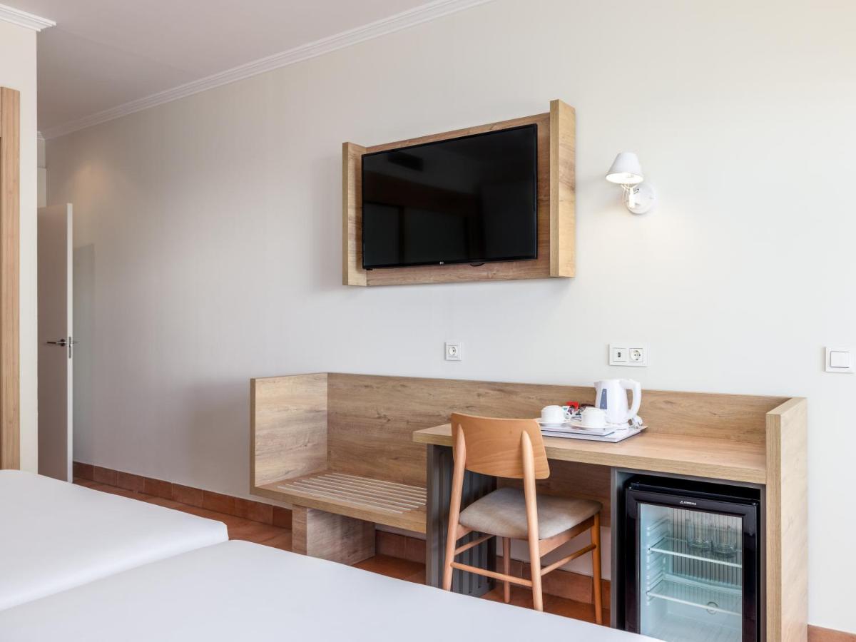 Una habitación de hotel con un escritorio y un televisor en la pared. en Playaballena, en Costa Ballena