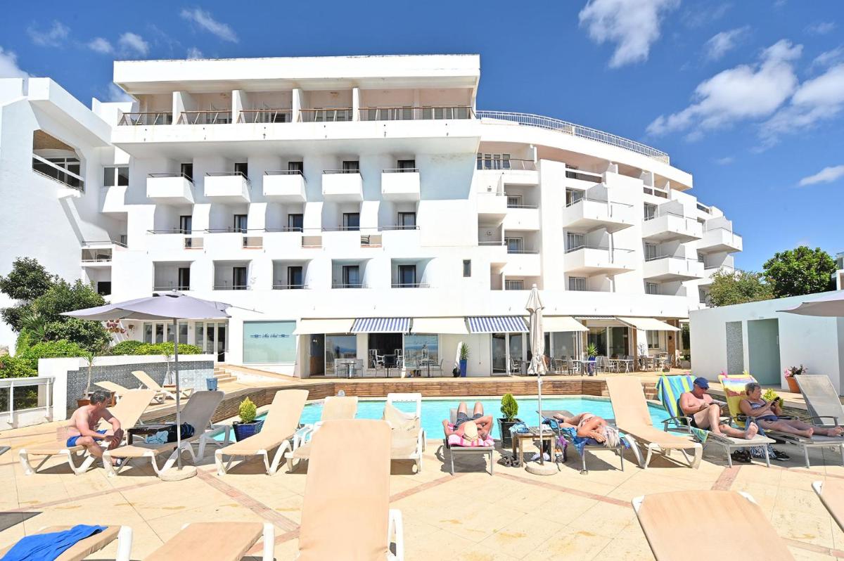 um hotel com piscina e pessoas sentadas em espreguiçadeiras em Boa Vista Hotel & Spa - Adults Only em Albufeira