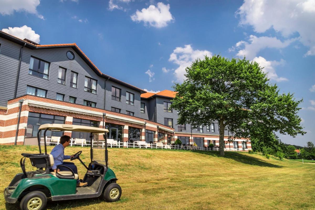 un homme conduisant une voiturette de golf dans un champ dans l'établissement Hôtel du Golf, à Lumbres