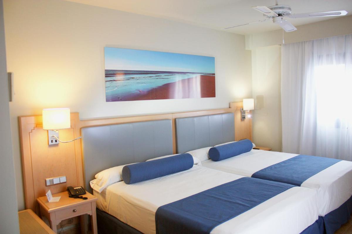 Un dormitorio con dos camas y un cuadro en la pared. en Playacanela, en Isla Canela