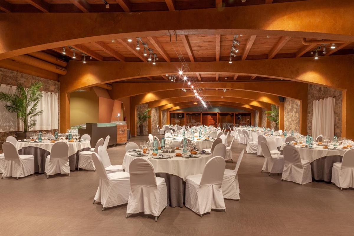 Un gran salón de banquetes con mesas y sillas blancas. en Montanyà, en Seva