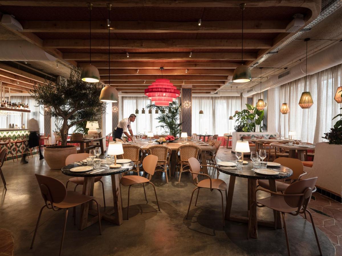 Un restaurante con mesas y sillas y gente al fondo. en Hesperia Sevilla, en Sevilla