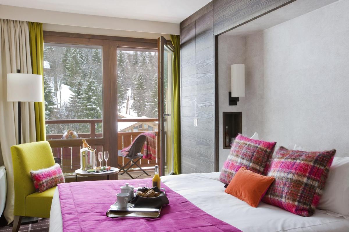 une chambre avec un lit avec une table et un balcon dans l'établissement Hotel Le Savoy, à Méribel