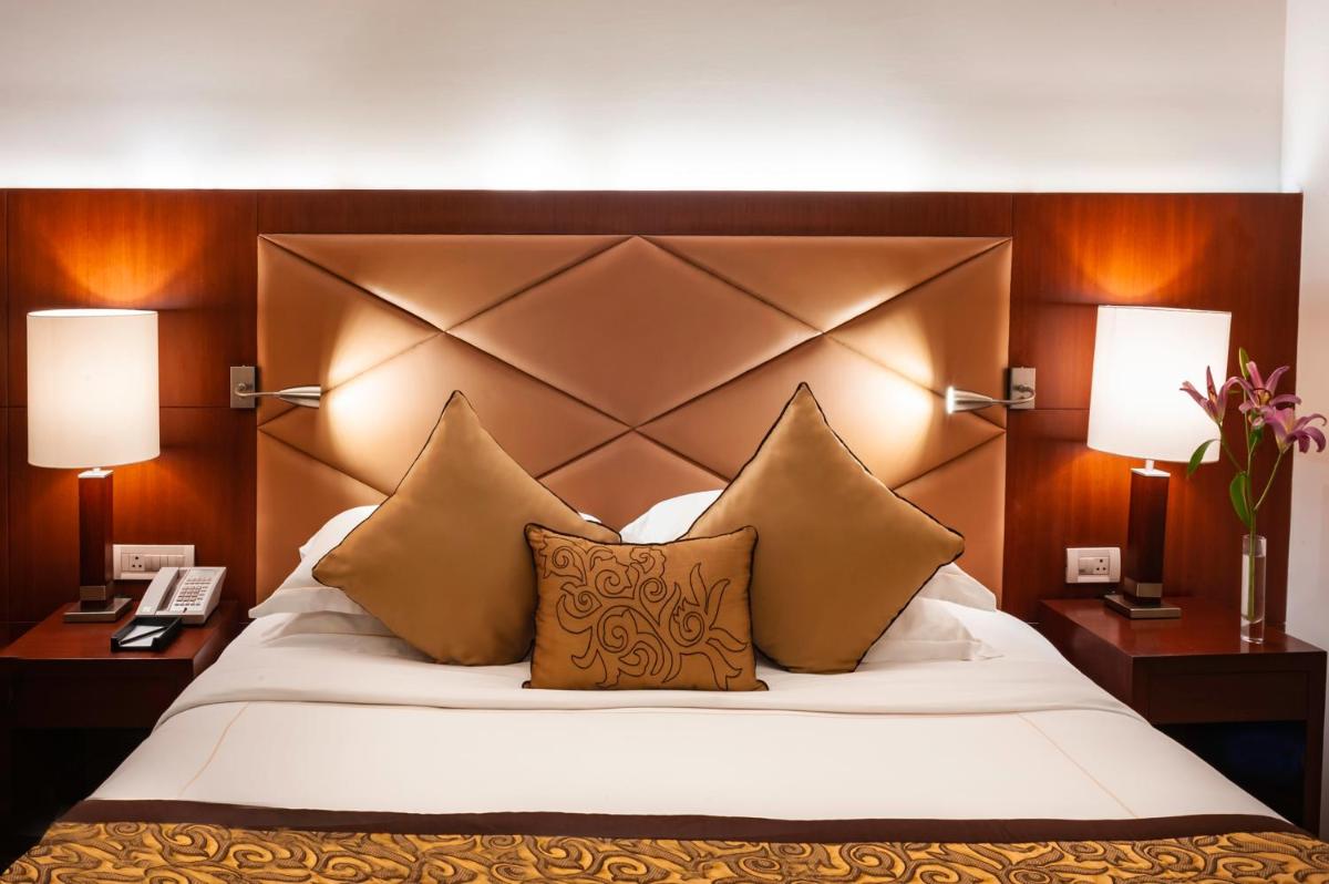 a bedroom with a large bed with pillows and two lamps at Taj Chandigarh in Chandīgarh