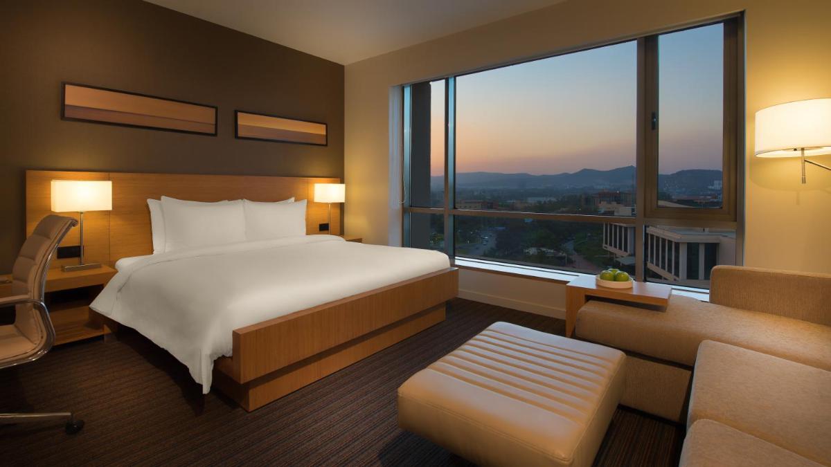 a hotel room with a bed and a large window at Hyatt Place Pune Hinjawadi in Pune