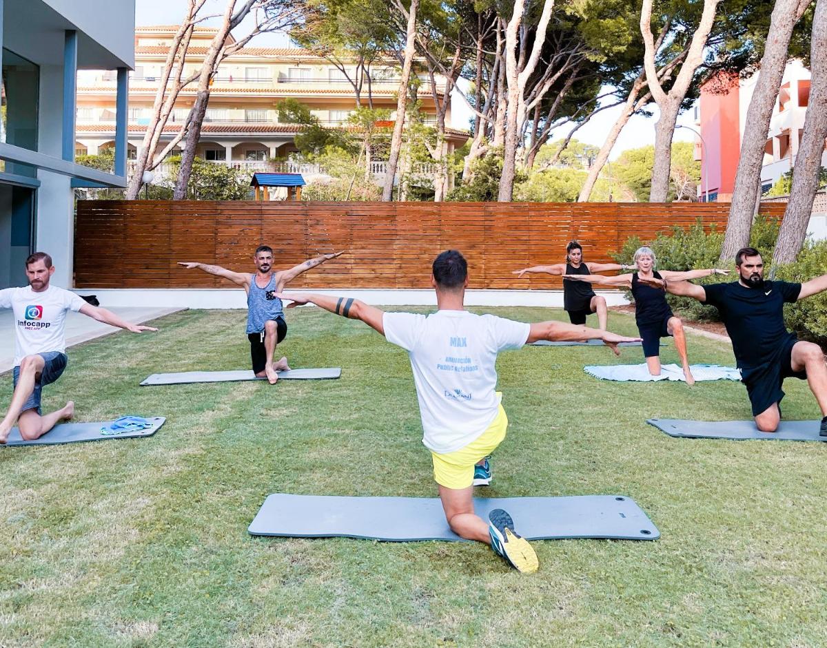 un grupo de personas haciendo yoga en la hierba en Diamant Hotel & Aparthotel, en Cala Ratjada