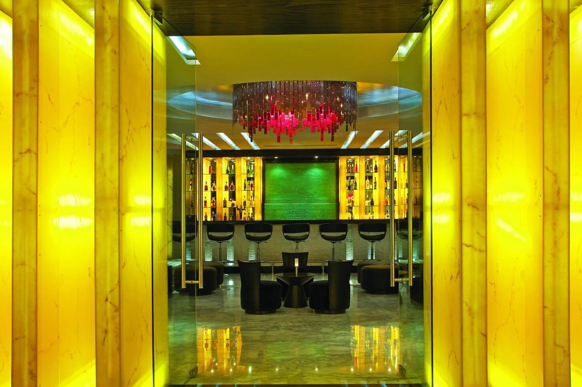 a room with a bar with chairs and a chandelier at Vivanta Hyderabad, Begumpet in Hyderabad a room with a bar with chairs and a chandelier at Vivanta Hyderabad, Begumpet in Hyderabad
