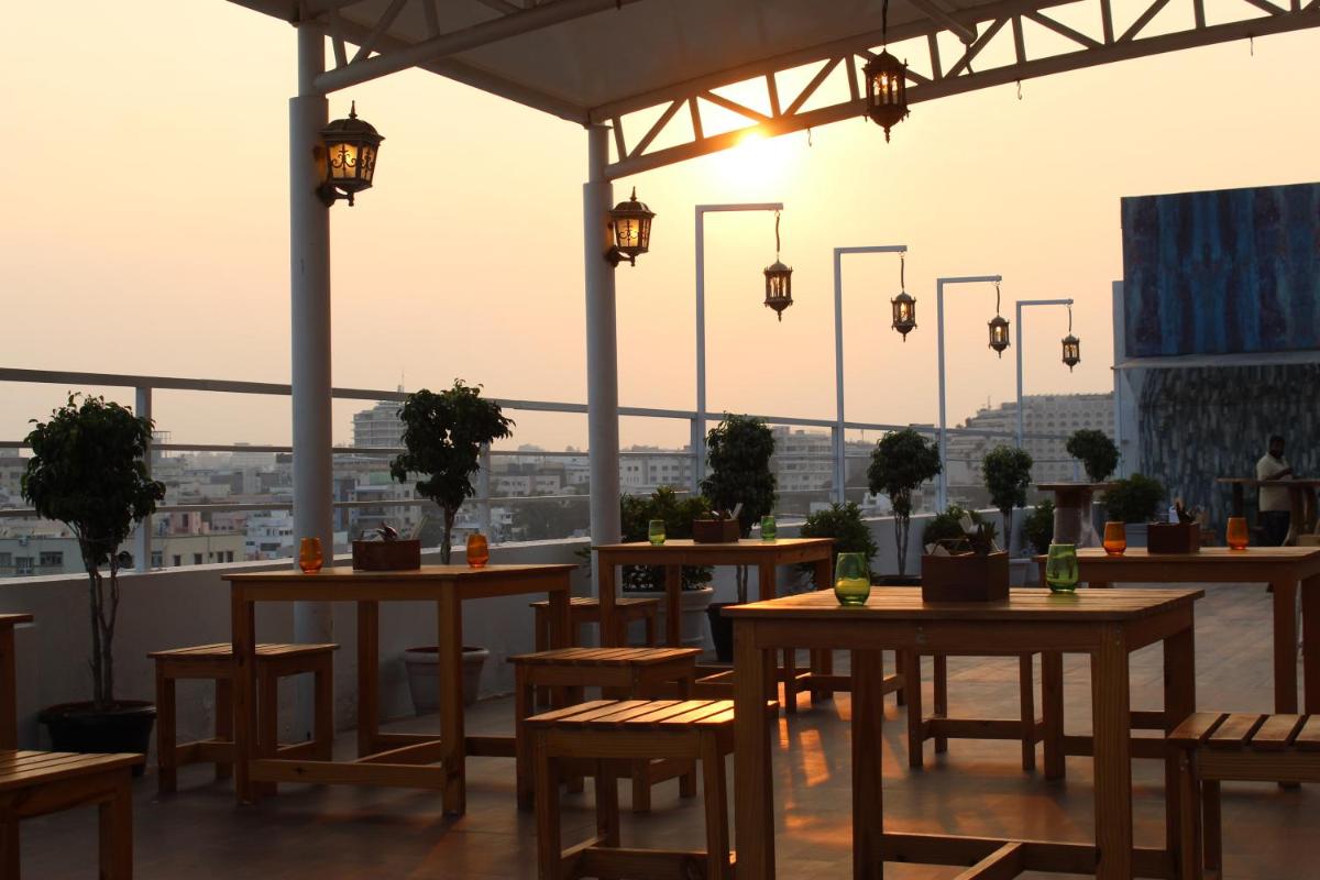 a restaurant with tables and chairs and a view of a city at Mercure Hyderabad KCP Banjara Hills, An Accor Hotel in Hyderabad