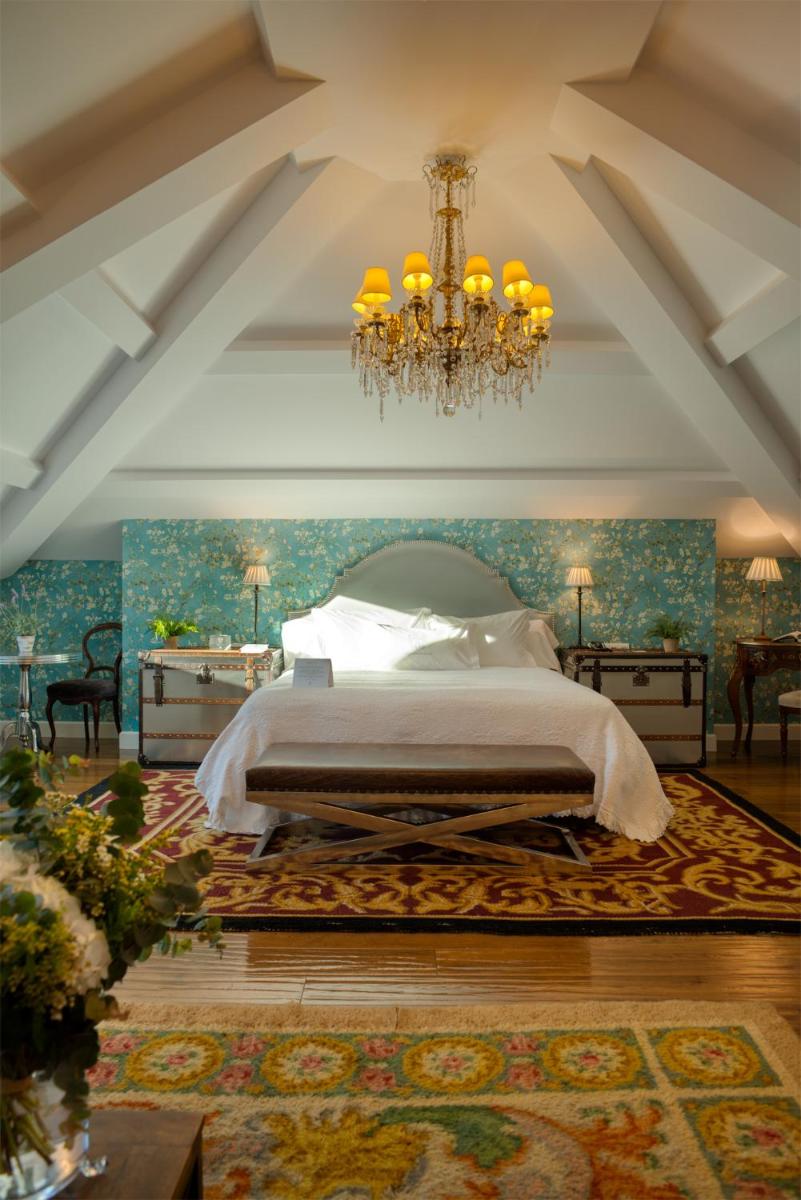 Un dormitorio con una cama grande y una lámpara de araña. en A Quinta Da Auga Hotel Spa Relais & Chateaux, en Santiago de Compostela