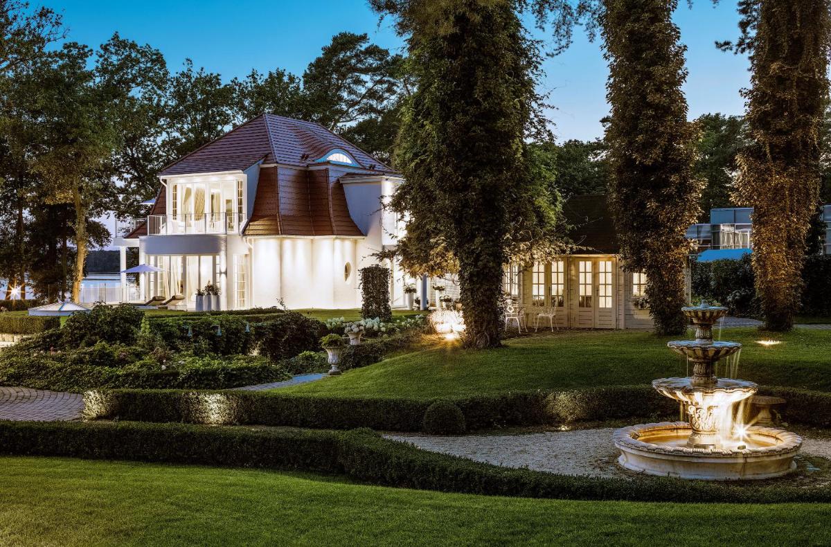 ein Haus mit einem Brunnen in der Mitte eines Gartens in der Unterkunft Villa Contessa - Luxury Spa Hotels in Bad Saarow