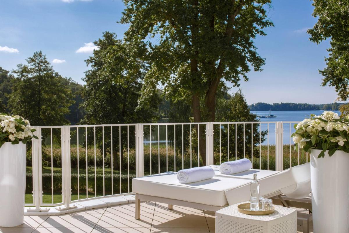 einen weißen Tisch auf einer Terrasse mit Blick auf das Wasser in der Unterkunft Villa Contessa - Luxury Spa Hotels in Bad Saarow