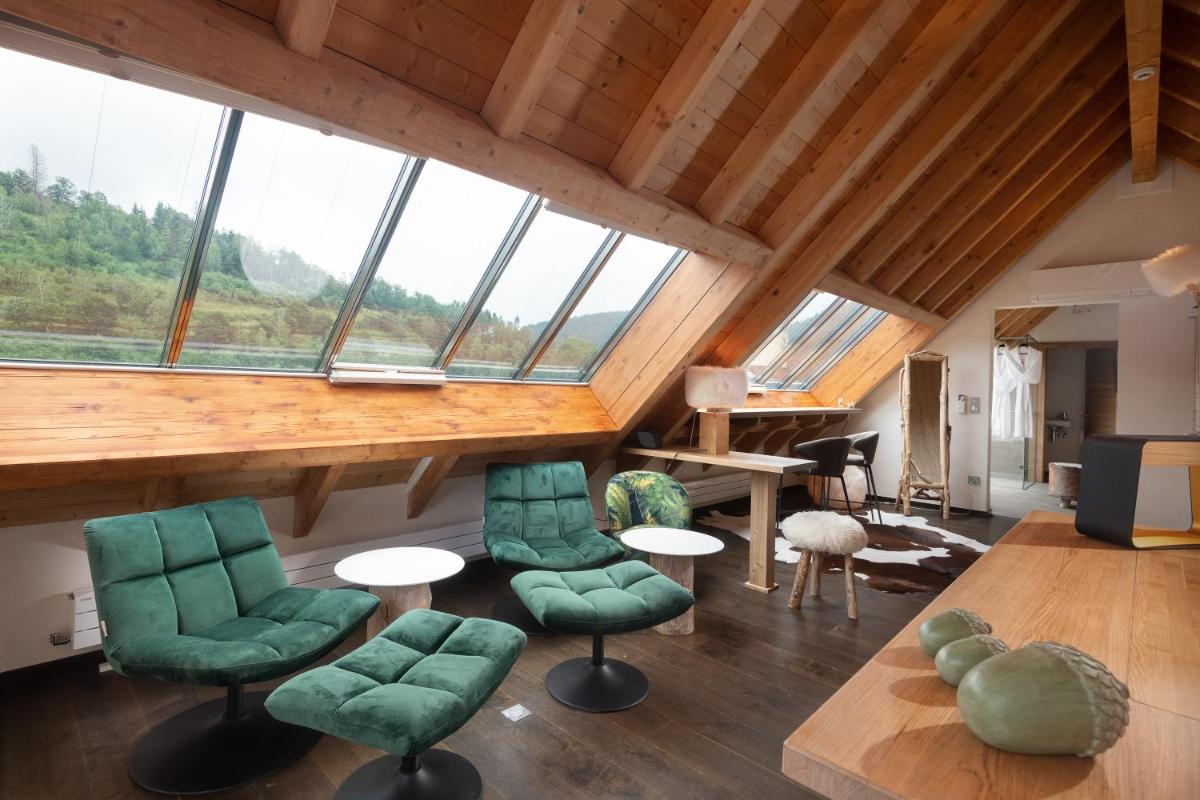 une pièce avec des chaises et des tables vertes et des fenêtres dans l'établissement LA CHENEAUDIÈRE - Hôtel Spa - Relais & Châteaux - Restaurant étoilé, à Colroy-la-Roche