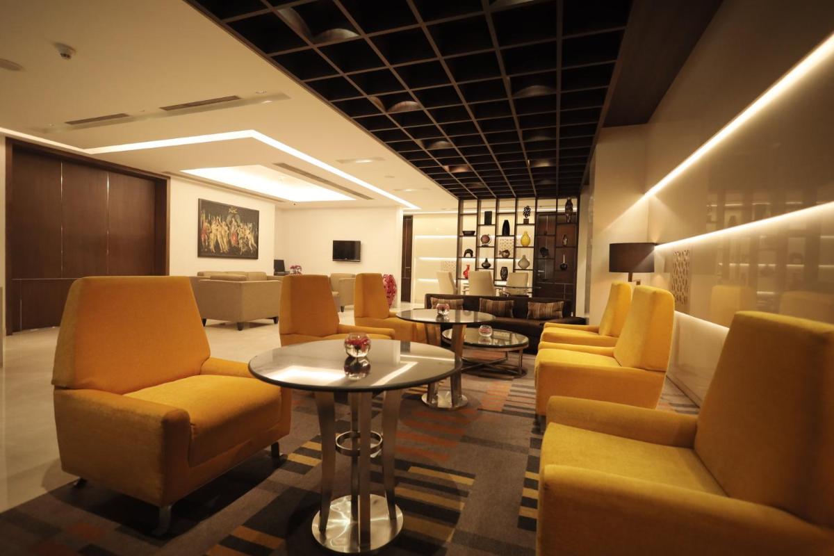 a waiting room with yellow chairs and a table at Holiday Inn Mumbai International Airport by IHG in Mumbai