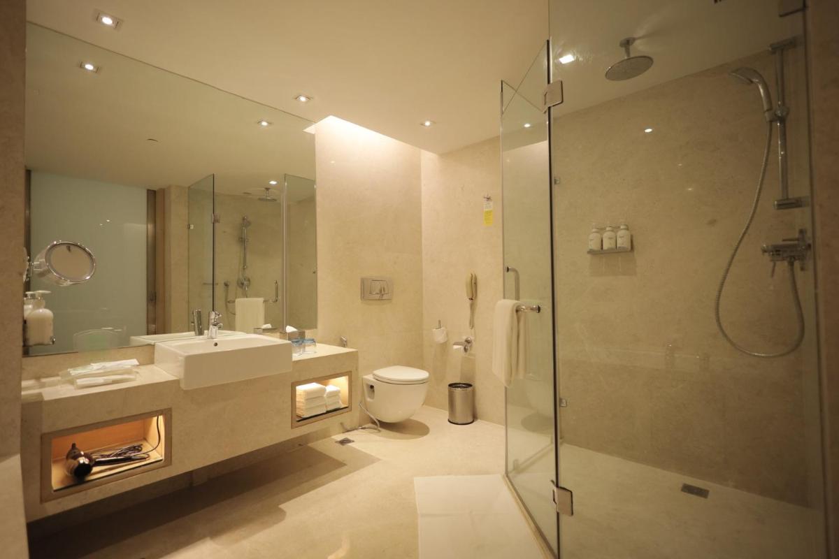 a bathroom with a shower and a sink and a toilet at Holiday Inn Mumbai International Airport by IHG in Mumbai
