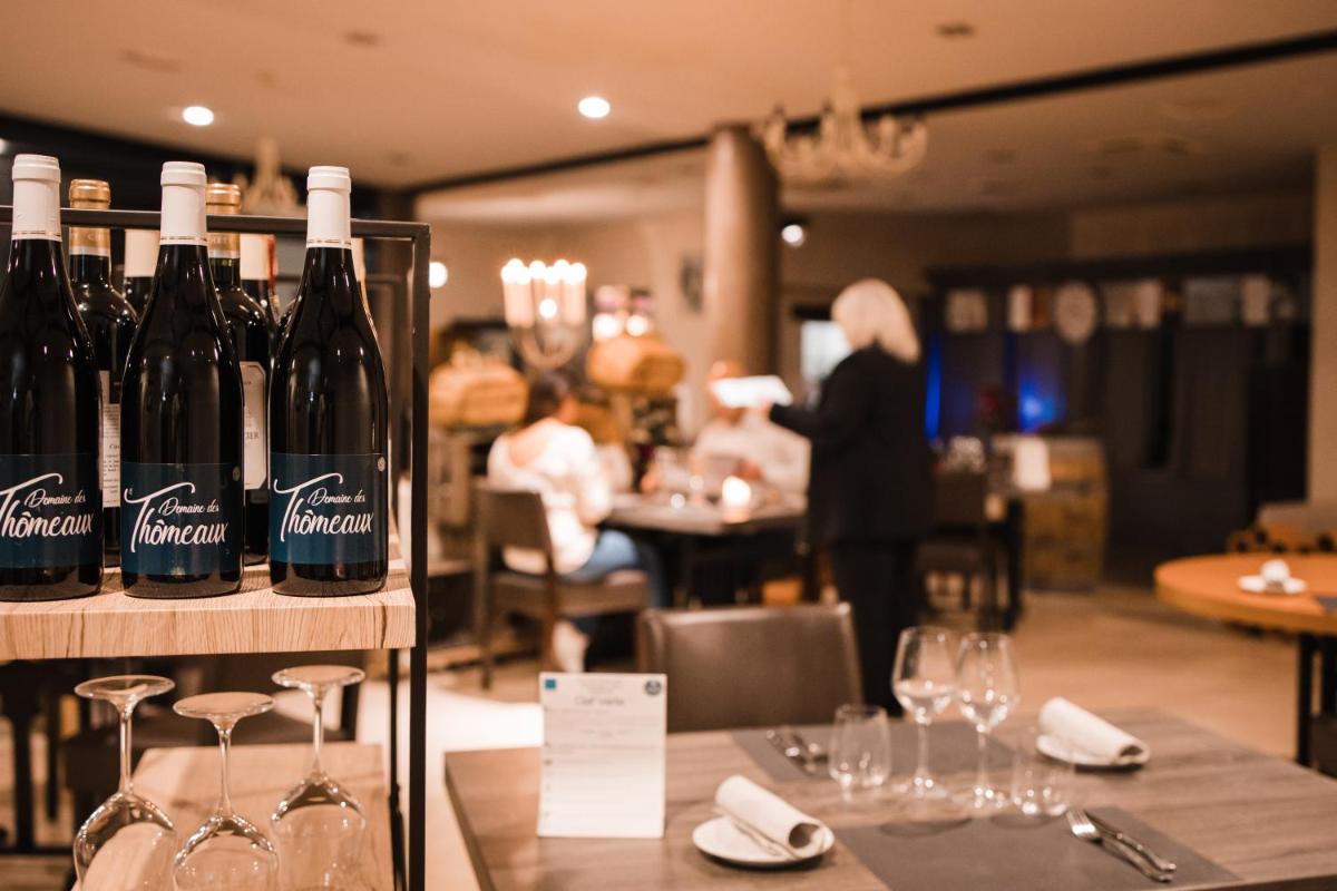- une table avec des bouteilles de vin dans un restaurant dans l'établissement Hôtel & Spa du Domaine des Thômeaux, The Originals Relais, à Mosnes