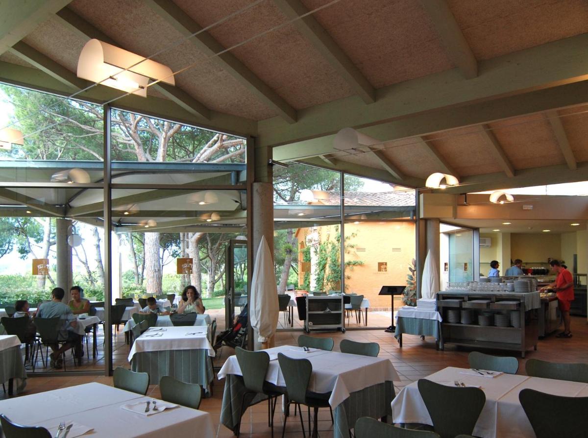 un restaurante con mesas blancas y gente sentada en mesas en Aparthotel Ciutat de Palol, en Platja d'Aro