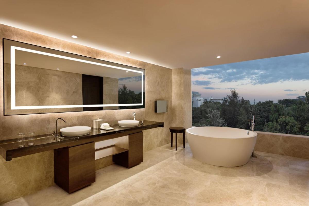 a bathroom with two sinks and a tub and a large window at Sheraton Grand Bengaluru Whitefield Hotel & Convention Center in Bengaluru a bathroom with two sinks and a tub and a large window at Sheraton Grand Bengaluru Whitefield Hotel & Convention Center in Bengaluru