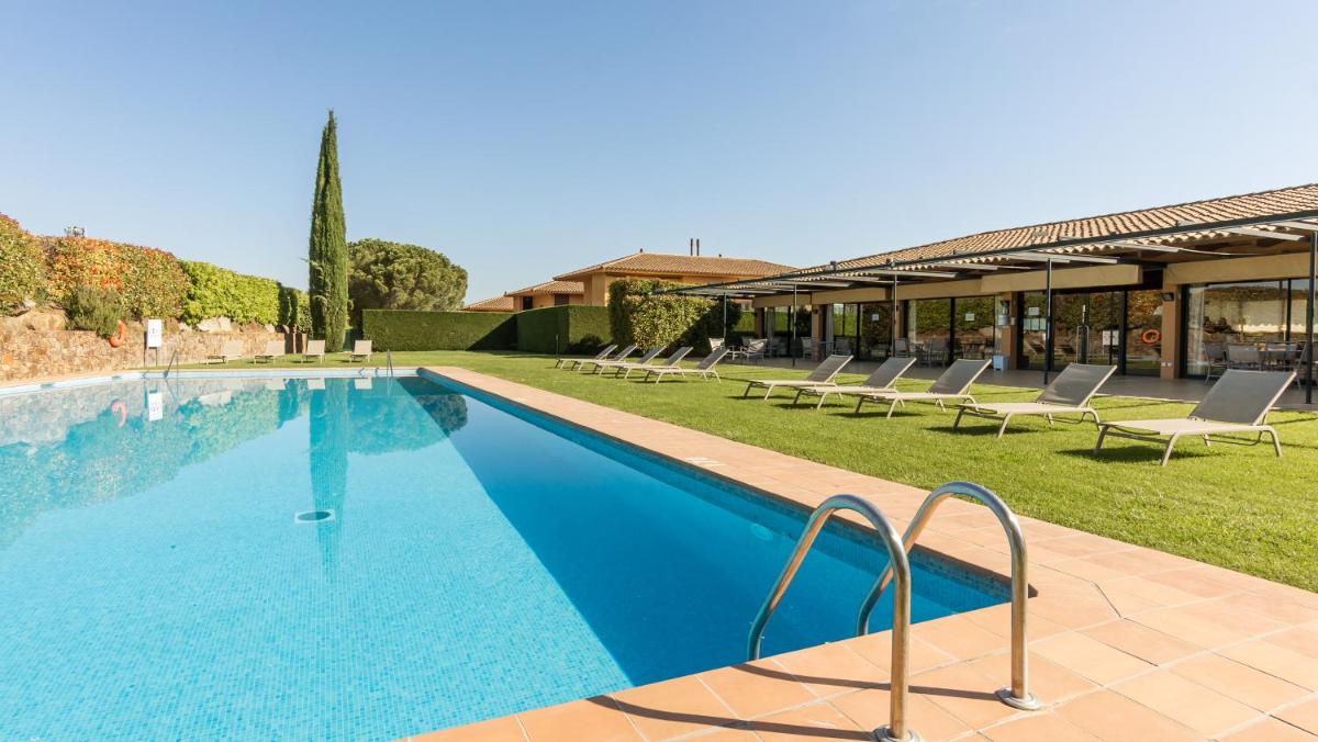 Una piscina con tumbonas al lado de un edificio. en Apartahotel Suites Vila Birdie, en Navata