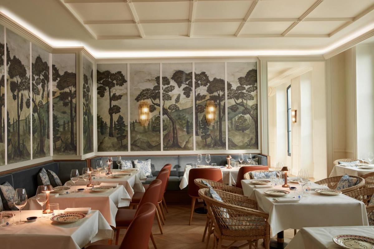 un restaurant avec des tables, des chaises et des peintures sur les murs dans l'établissement Maison Delano Paris, à Paris 96 autres photos