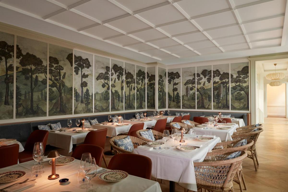 une salle à manger avec des tables et des chaises et des tableaux aux murs dans l'établissement Maison Delano Paris, à Paris