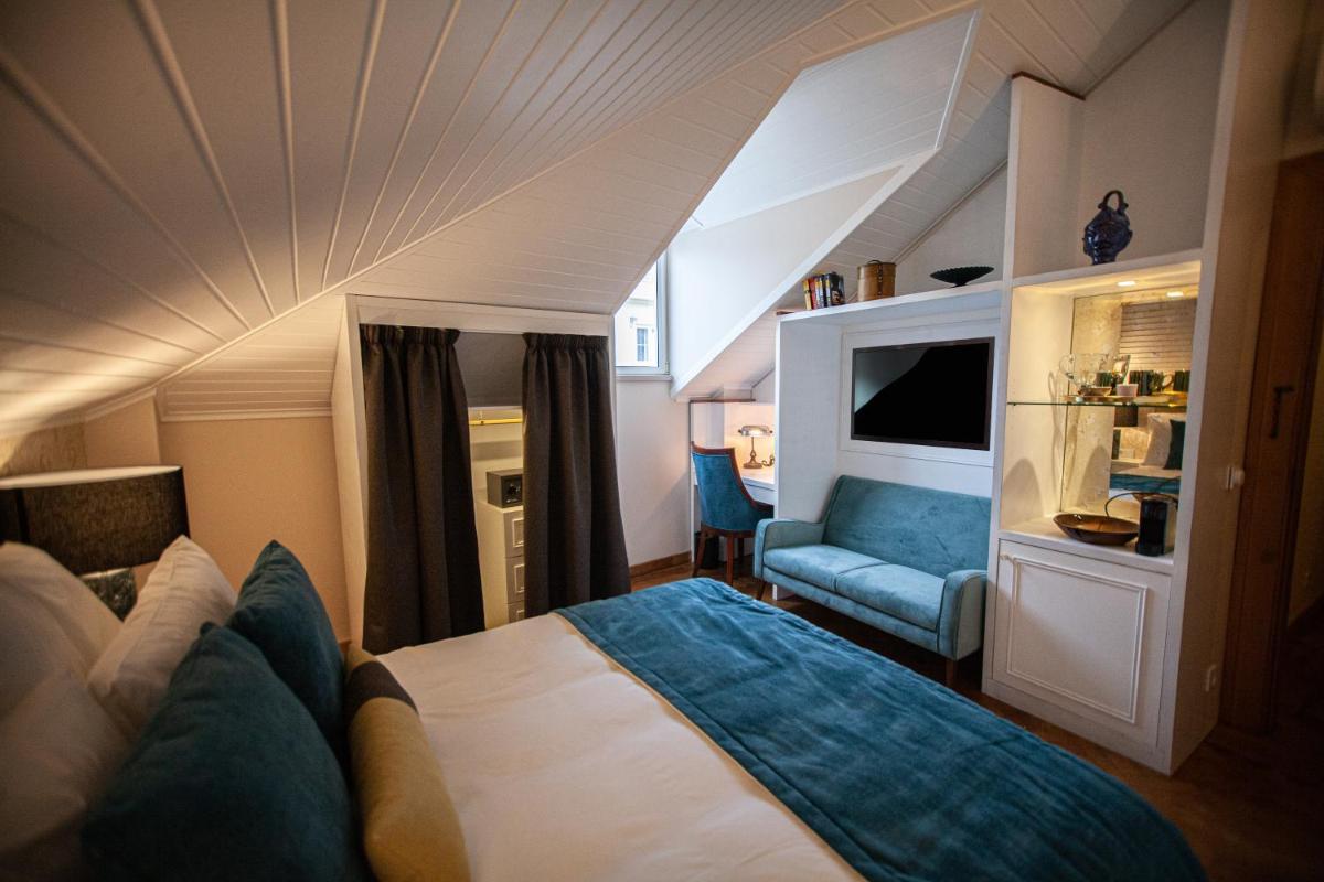 um quarto com uma cama e uma cadeira em um cômodo em Storytellers Palace em São Martinho do Porto