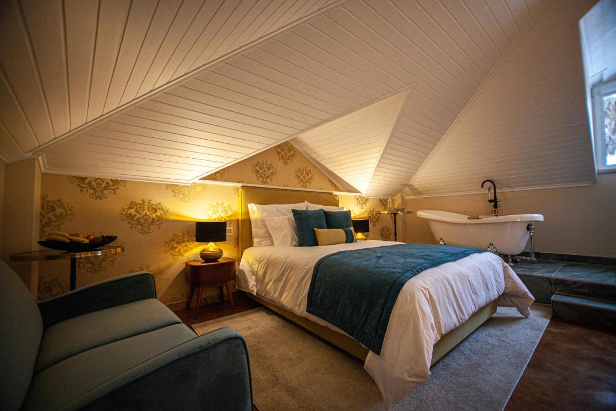 um quarto com uma cama e um lavatório no sótão em Storytellers Palace em São Martinho do Porto