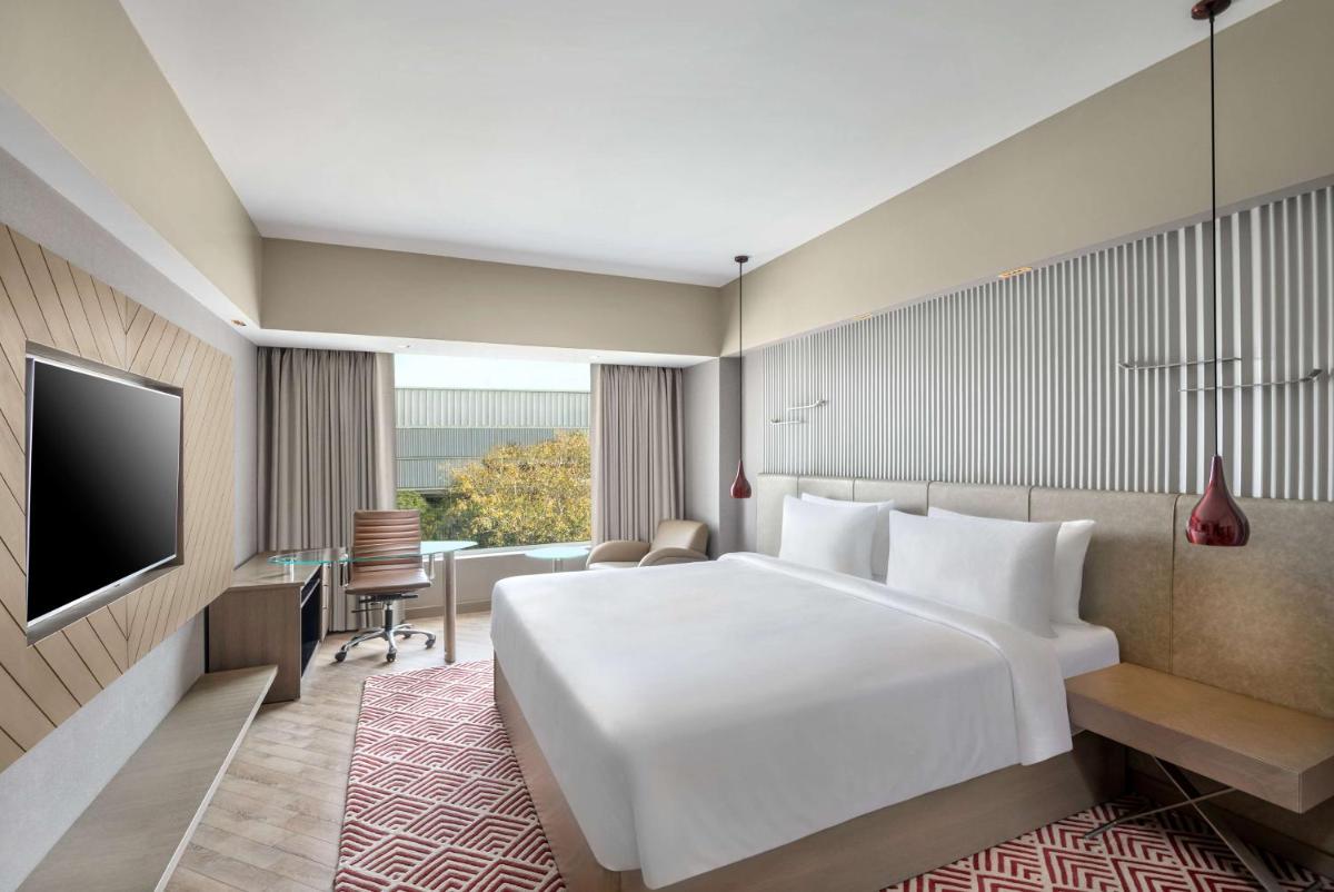 a hotel room with a large white bed and a desk at Radisson Hotel Sector 29 Gurugram in Gurgaon