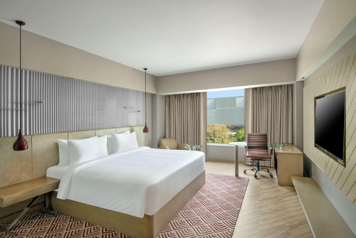 a hotel room with a bed and a desk and a tv at Radisson Hotel Sector 29 Gurugram in Gurgaon a hotel room with a bed and a desk and a tv at Radisson Hotel Sector 29 Gurugram in Gurgaon
