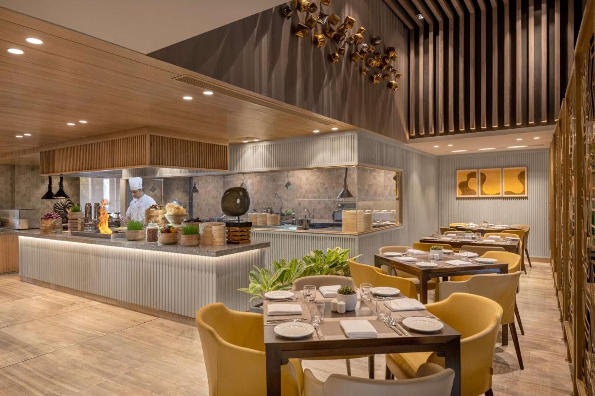 a restaurant with tables and a chef in the kitchen at Radisson Hotel Sector 29 Gurugram in Gurgaon
