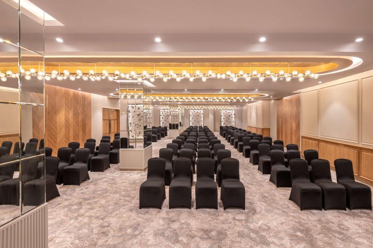 a conference room with black chairs and a stage at Radisson Hotel Sector 29 Gurugram in Gurgaon