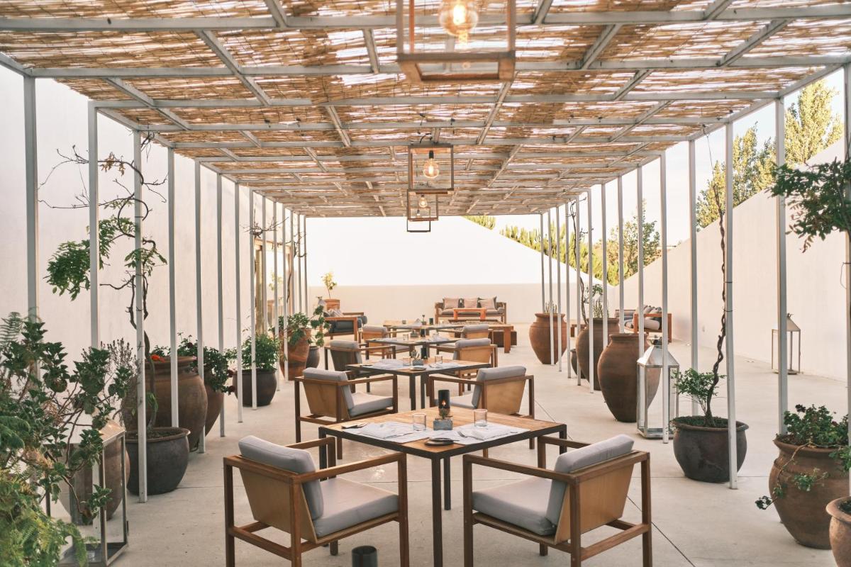 um restaurante com mesas e cadeiras e vasos de plantas em L'AND Vineyards - Relais & Châteaux em Montemor-o-Novo