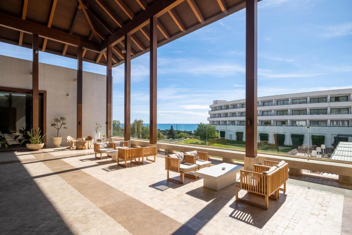 Un patio con sillas y mesas y un edificio. en Eurostars Sitges, en Sitges