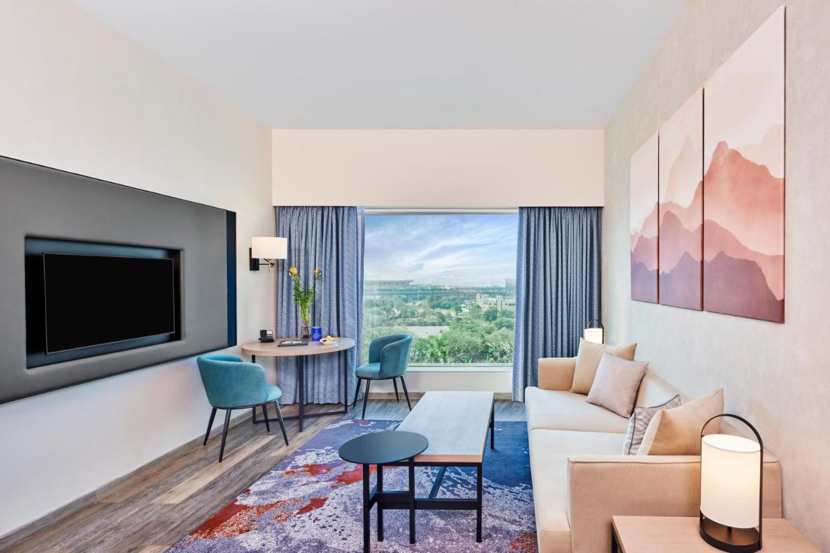 a living room with a couch and a tv at Novotel Mumbai International Airport in Mumbai