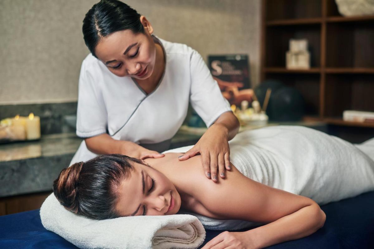 a woman receiving a massage from a therapist at Novotel Mumbai International Airport in Mumbai